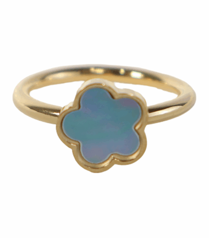 Primer plano de un anillo de banda dorada simple con un adorno central en forma de flor de cuatro pétalos. El adorno está relleno de nácar azul aqua iridiscente y tiene un borde dorado fino.