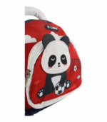 Detalle de una mochila infantil roja con cremallera blanca y un parche bordado de un panda sosteniendo un balón de fútbol sobre un fondo de portería y nubes.