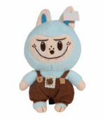 Peluche Labubu azul celeste de cuerpo suave y orejas grandes. Viste un overol de pana marrón con tirantes y parches decorativos